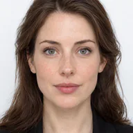 Olivia Maria Colman, with shoulder-length brown hair and a black blazer, facing the camera on a white background